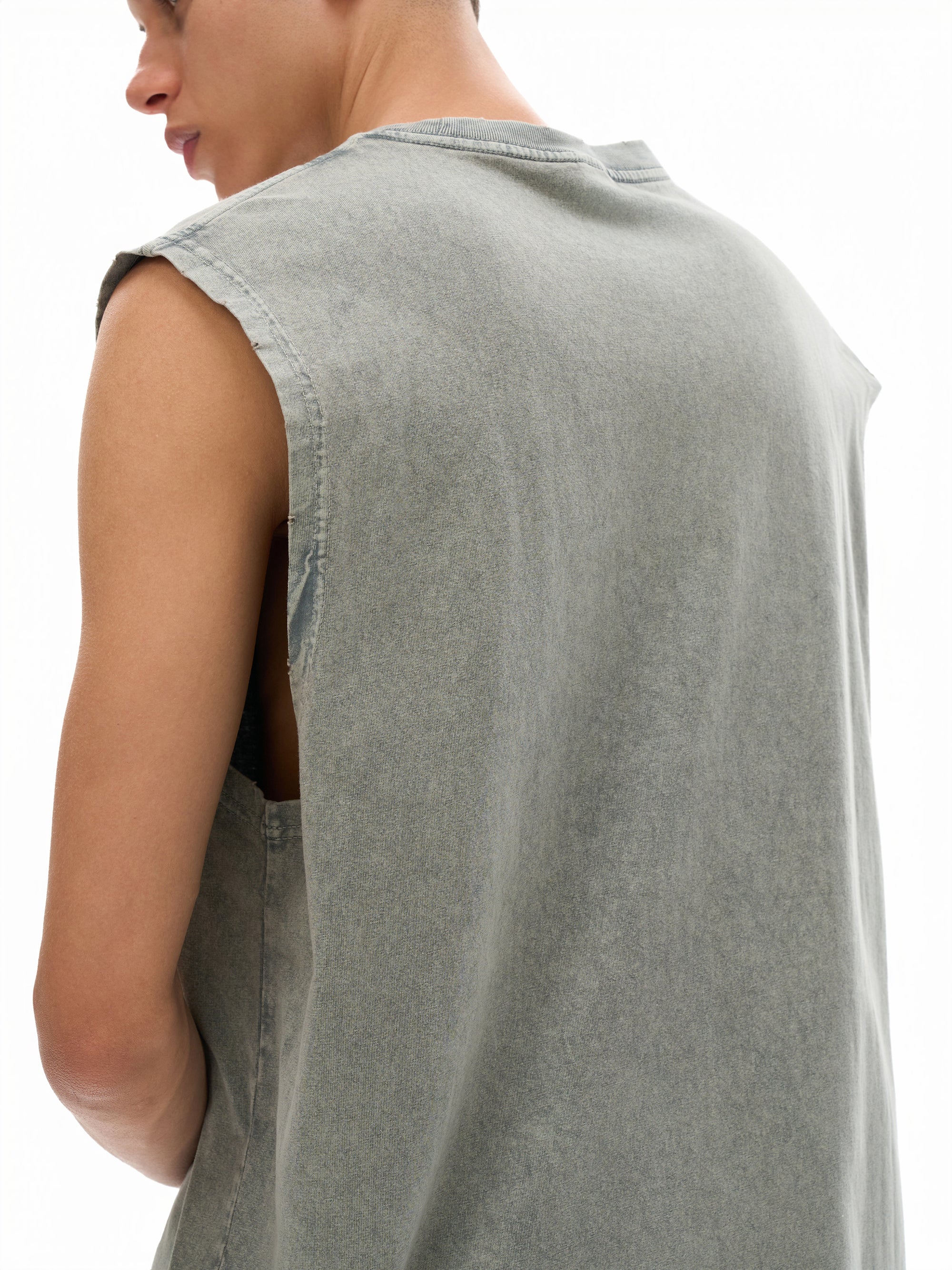 Person wearing a sleeveless green denim shirt on a white background